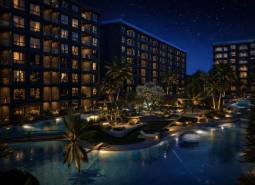 Noční výstavba bytů v Pattaye s osvětlenými budovami a bazénem.