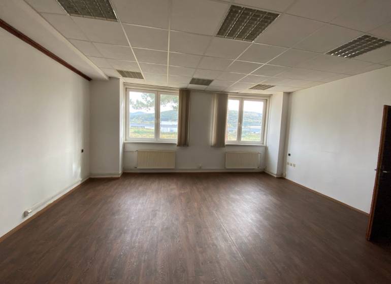 Kancelářský prostor s tmavou podlahou a oknem s výhledem.