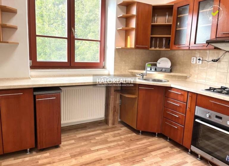 Kuchyně ve 3-pokojovém bytě s dřevěnou linkou, okno s výhledem do zeleně.