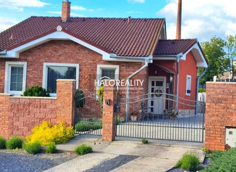 Rodinný dům v Kalinově s cihlovou fasádou, ozdobným plotem a zahradními prvky.