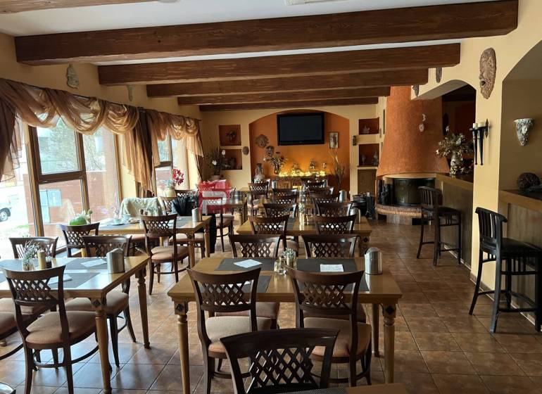 Restaurace s dřevěnými stropy, květinovou dekorací a krbem, kategorie Hotely a penziony.