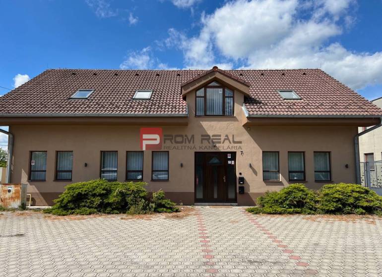 Výrobní prostory na Nové ulici v Pezinku s velkou vydlážděnou plochou před budovou.
