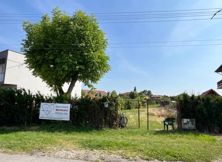 Pozemky - bydlení v obci Dolní Bar, oplocený pozemek se stromem a bránou.