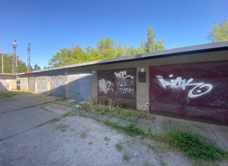 Garáže ve Zvolenu s graffiti na vratech, obklopené zelení a betonovou plochou.