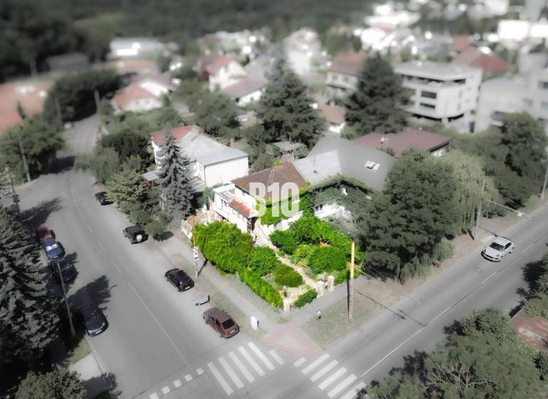Rodinný dům v lokalitě Bratislava - Staré Město, obklopený zelení a cestou s auty.