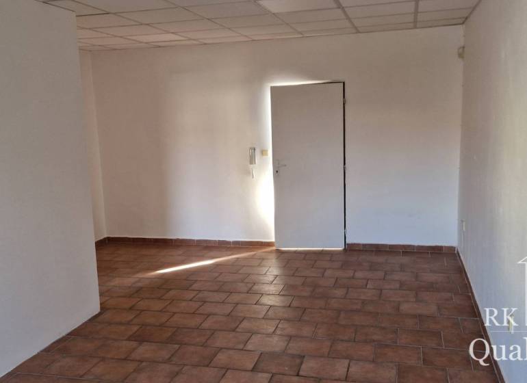 Interiér budovy s bílými stěnami a dlažbou na podlaze.