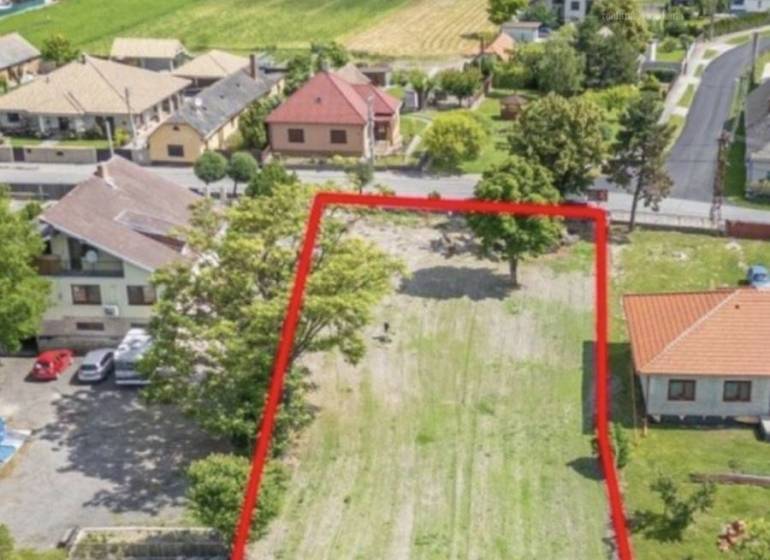 Pozemek k bydlení v Čiližské Radvani, obklopený domy a zelení, nabízí krásné výhledy.