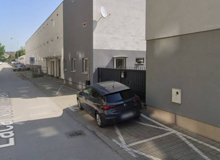 Auto parkující u budovy na ulici Laca Novomeského v Pezinku, u garáží.