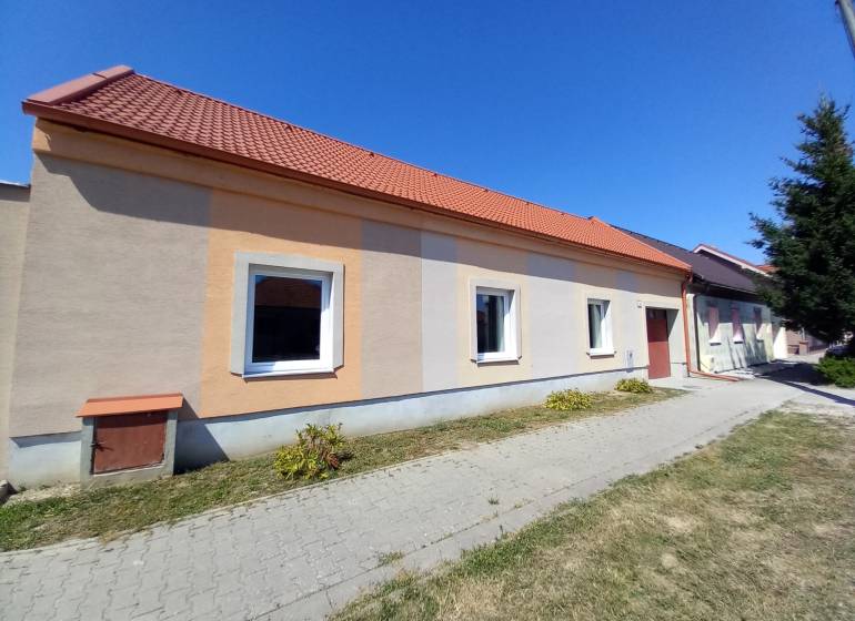 Rodinný dům v Trakovicích s oranžovou fasádou a červenou střechou.