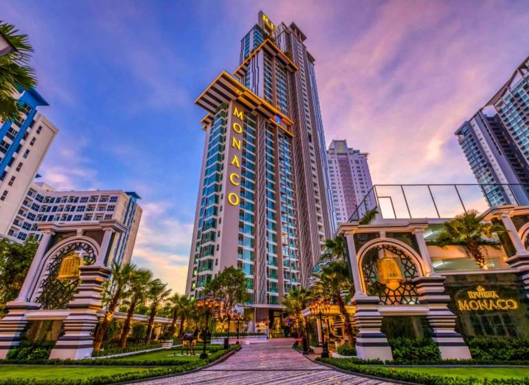 Výšková budova Monaco v centru výstavby bytů ve městě Pattaya, obklopená palmami.