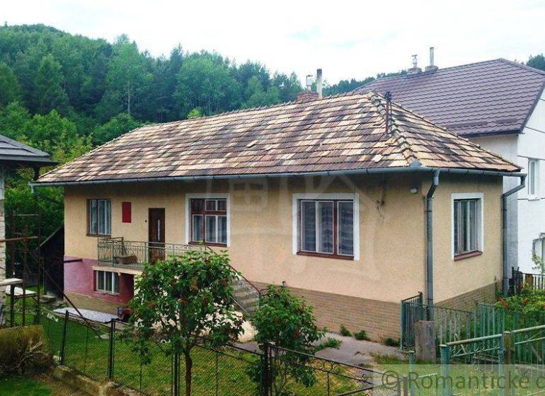 Rodinný dům ve Fričovcích se šikmou střechou, zahradou a okolním lesem.