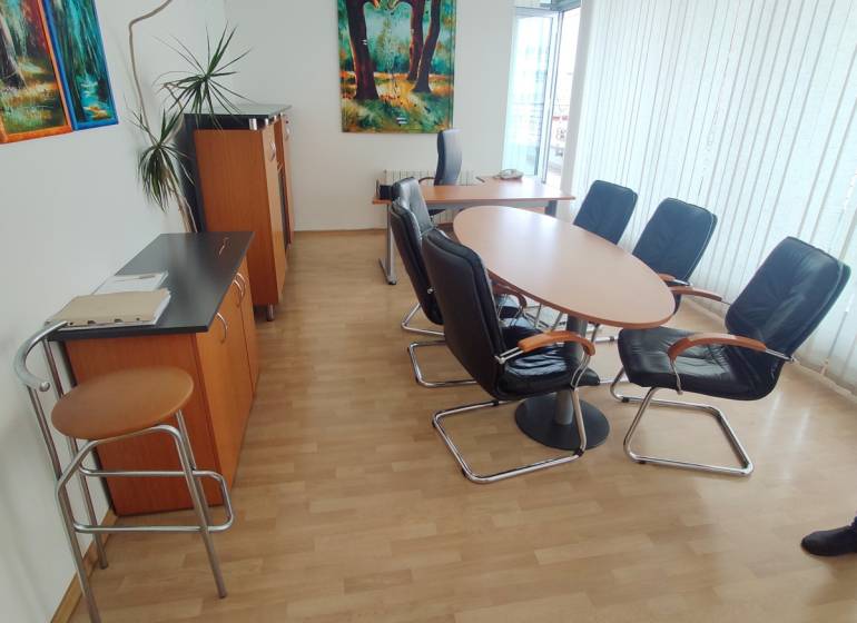 Kanceláře s kulatým stolem a židlemi, na zdi visí obraz.
