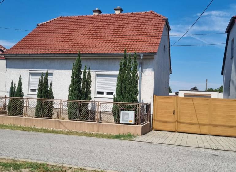 Rodinný dům na Riadku v Malackách s červenou střechou, předzahrádkou a dřevěnou bránou.