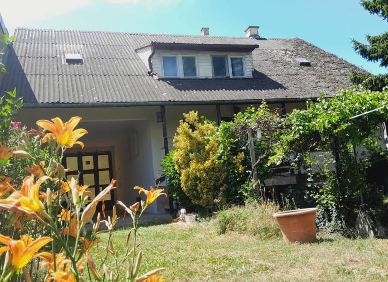 Rodinný dům v Potzneusiedlu s květinovou zahradou, vinicí a tradičním šikmým střešním designem.