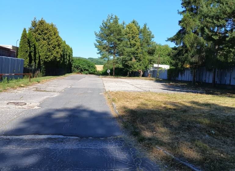Asfaltová cesta obklopená stromy a zelení v Prievidzi, vhodná na pozemky - bydlení.