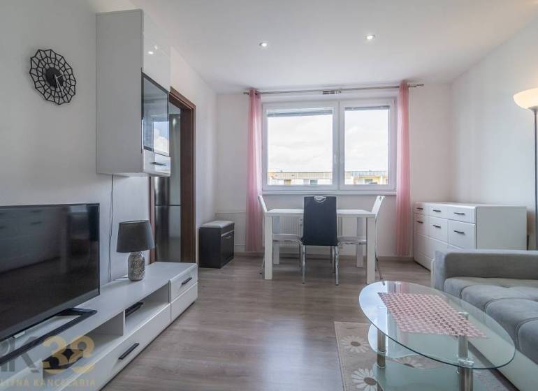 Světlý obývací pokoj se stolem, televizí a sedačkou v 3-pokojovém bytě.