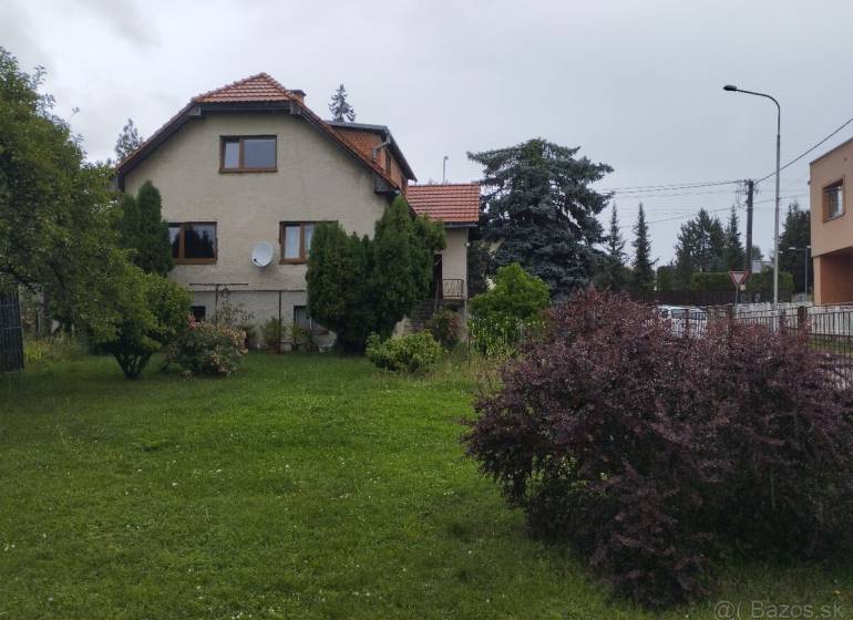 Rodinný dům v Martině, s upravenou zahradou a obklopený stromy a keři.