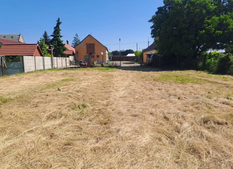 Zahrada u rodinného domu ve Sládkovičově s upraveným trávníkem a ohradou.