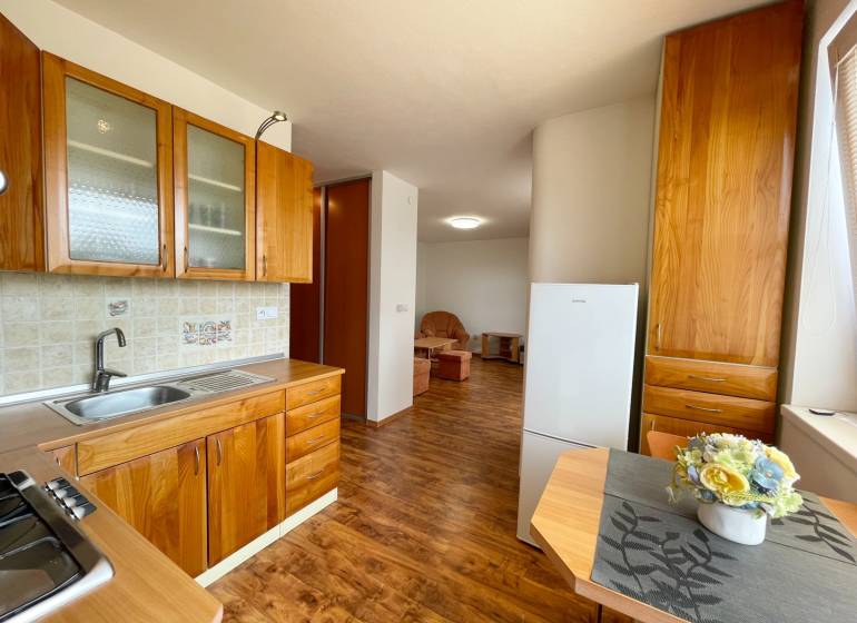 Dřevěná kuchyně s jídelním stolem a pohled do obývacího pokoje, 2-pokojový byt.
