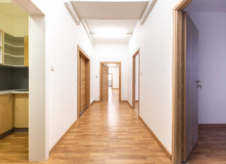 Chodba s dřevěnou podlahou a dveřmi v kanceláři.