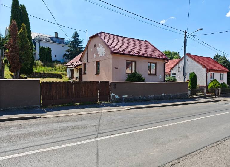 Rodinný dům na Dlouhé ulici ve Vranově nad Topľou s červenou střechou a dřevěným plotem.