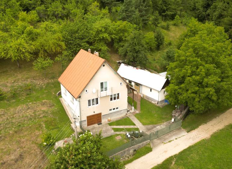Rodinný dům v Papradně obklopený travnatým pozemkem a stromy, přístupová cesta.