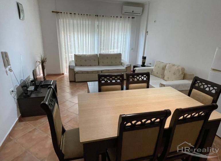 Interiér rekreačního apartmánu s jídelním stolem, pohodlnými sedačkami a televizí.