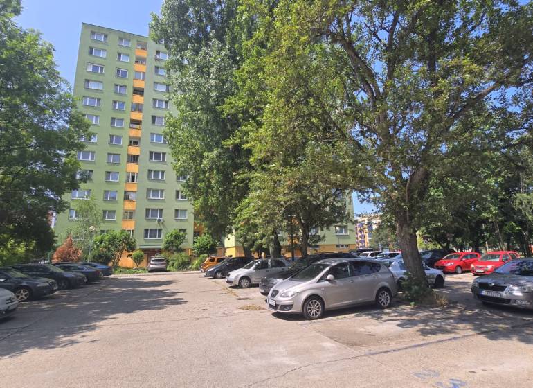 Parkoviště v Bratislavě - Petržalce na ulici Osuského s výhledem na bytové domy a zeleň.