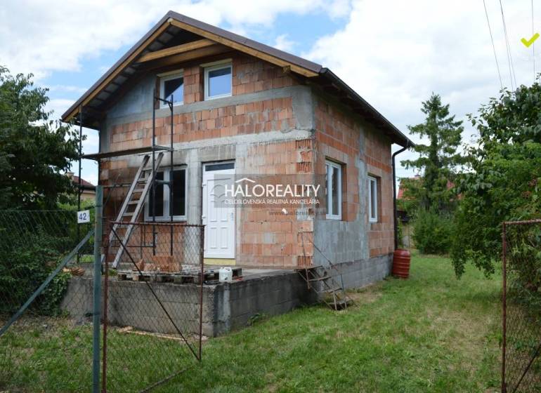Chata ve Vinosadech postavená z cihel, s žebříkem a zeleným okolím.