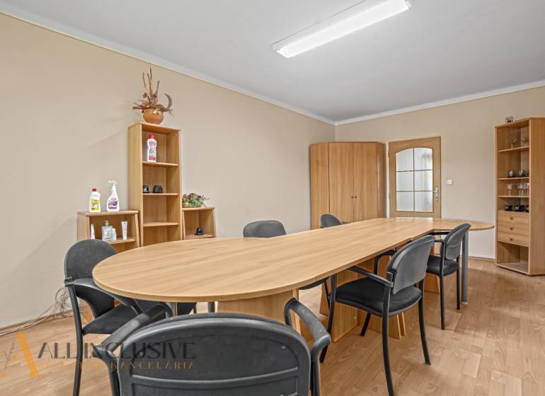 O zasedací místnosti: dřevěný stůl, židle, skříně a police v kanceláři.