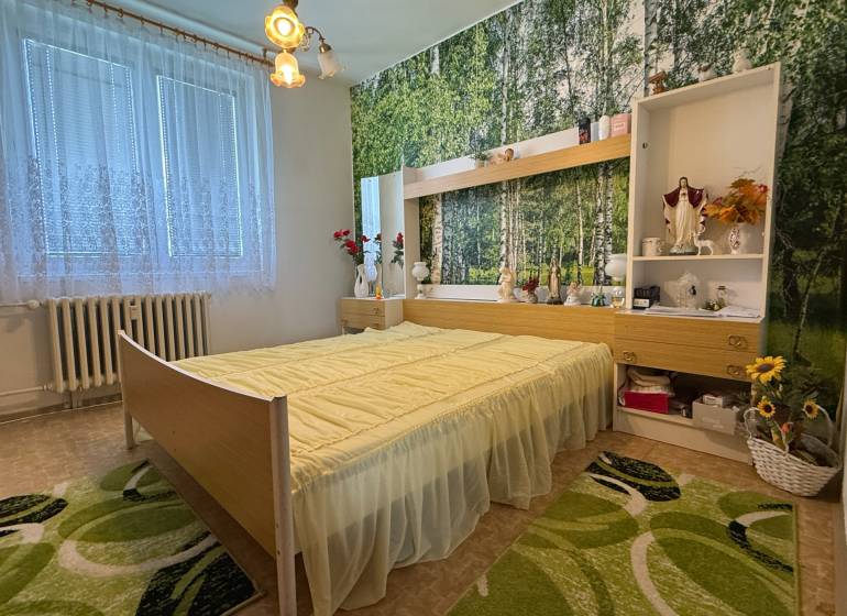 Ložnice ve 3pokojovém bytě s květinovou výzdobou a lesní tapetou na stěně.
