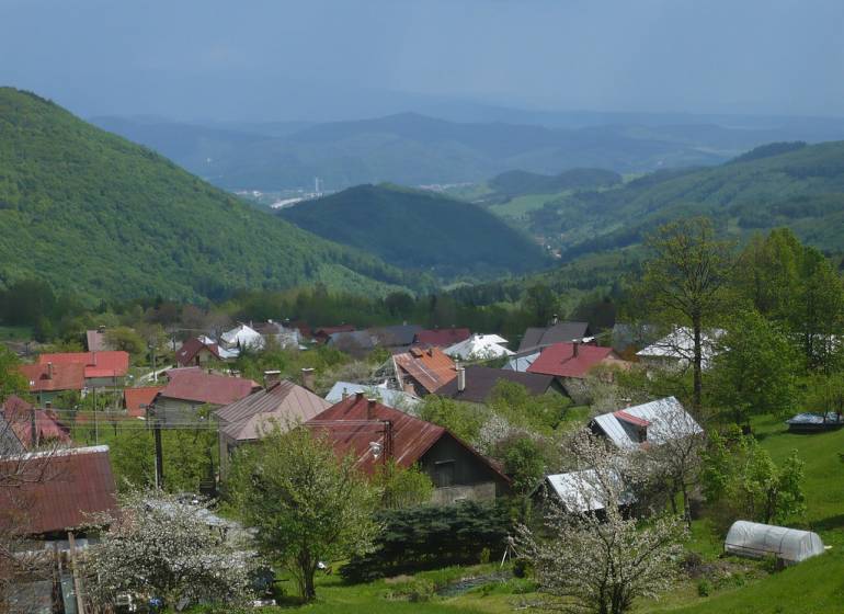 Pohled na chaty v Kordíkách u Banské Bystrice s malebnými kopci v pozadí.