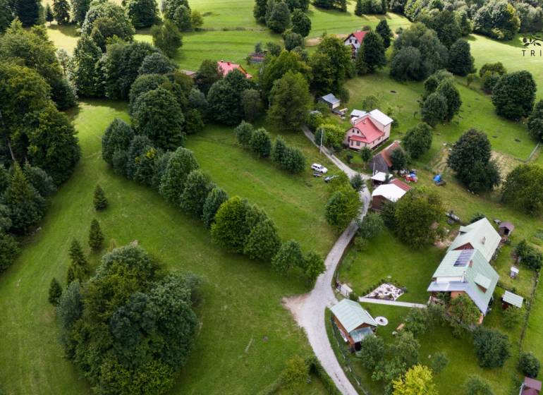 Letecký pohled na rekreační pozemky v Oščadnici obklopené hustou zelení a domy.