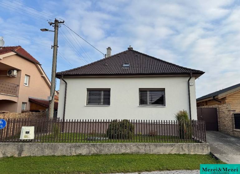 Rodinný dům v Trstíně se šikmou střechou, oplocení a travnatá plocha před domem.