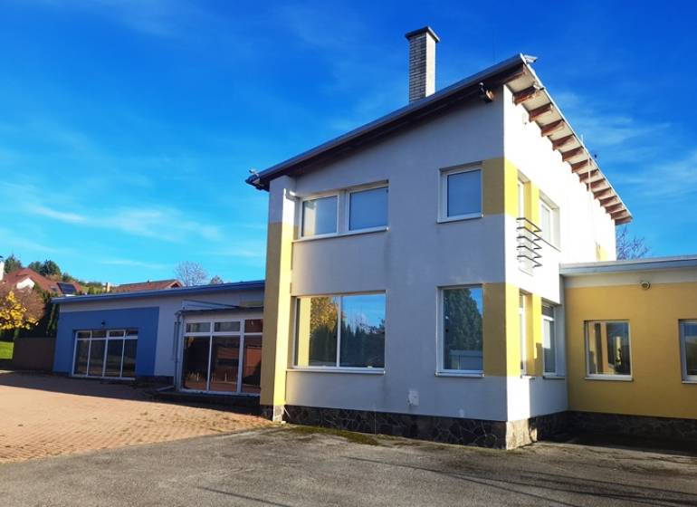 Rodinný dům v Necpalech, barevná fasáda, velký dvůr, slunečný jasný den.