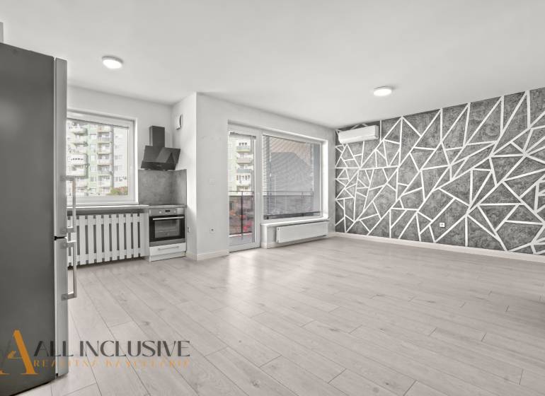 Kuchyně a obývací pokoj v 2-pokojovém bytě s podlahou s dřevěným dekorem a geometrickou stěnou.