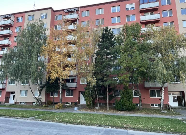 Bytový dům na Hviezdoslavově ulici v Senici s okolní zelení a stromy.