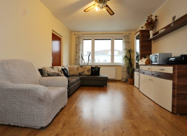 Obývací pokoj s pohovkou a skříňkami, podlaha s dřevěným dekorem, 3-pokojový byt.