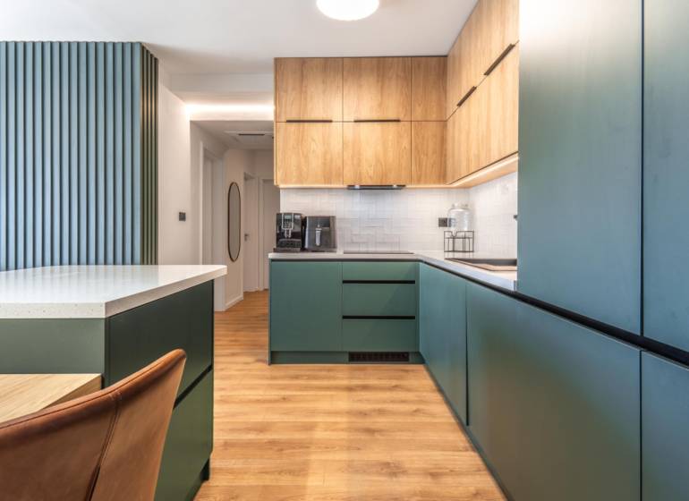 Kuchyně ve 3-pokojovém bytě s podlahou s dřevěným dekorem a zelenými skříňkami.