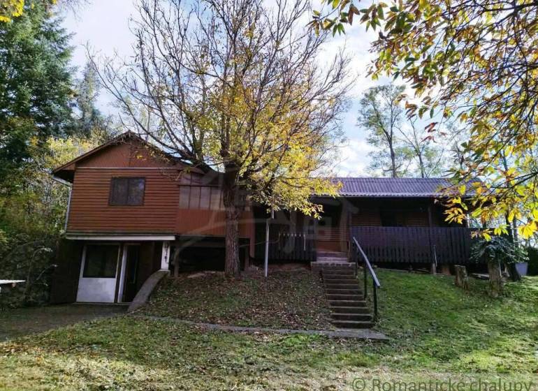 Chata v Dudincích obklopená stromy a svěží zelení, ideální na odpočinek.