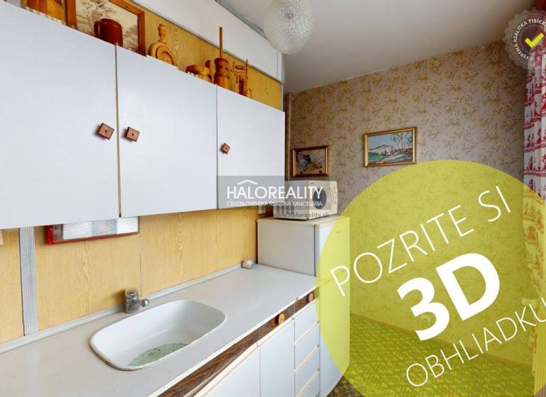 Kuchyně ve 3-pokojovém bytě s bílými skříňkami a obrázky na stěnách.