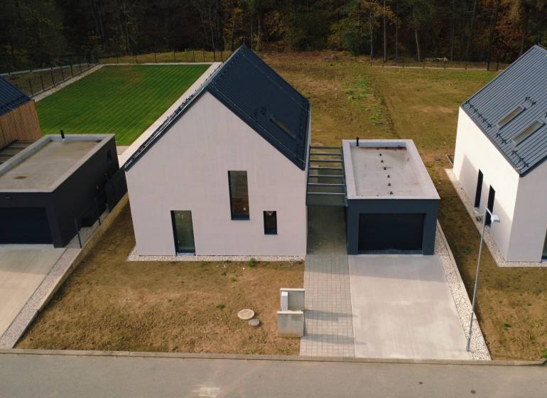 Rodinné domy na ulici Pod Drieňovou v Kamenici nad Cirochou obklopené trávníkem a příjezdovou cestou.