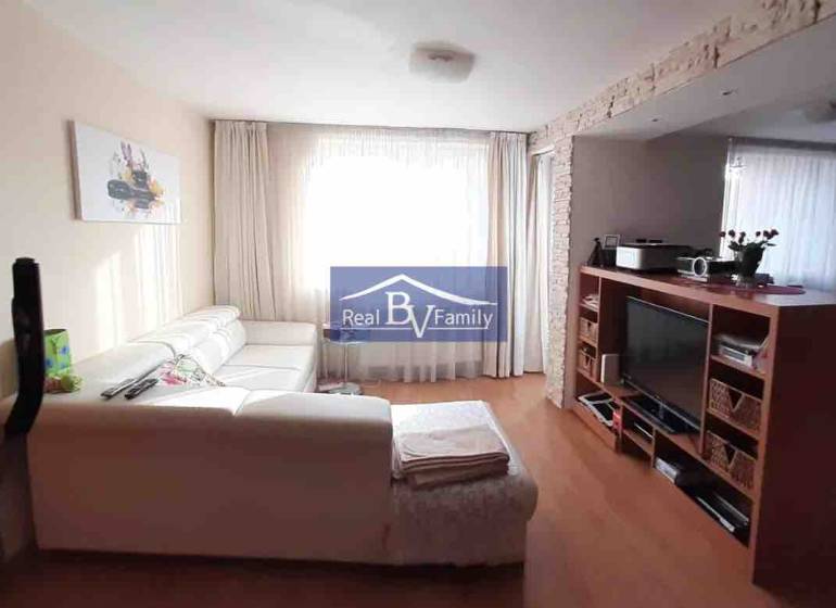 Obývací pokoj s bílou sedačkou a televizorem, podlaha s dřevěným dekorem, 2pokojový byt.