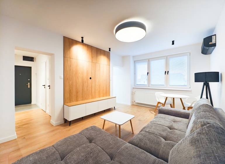 Obývací pokoj s pohovkou, jídelním stolem, dřevěnou podlahou v 2pokojovém bytě.