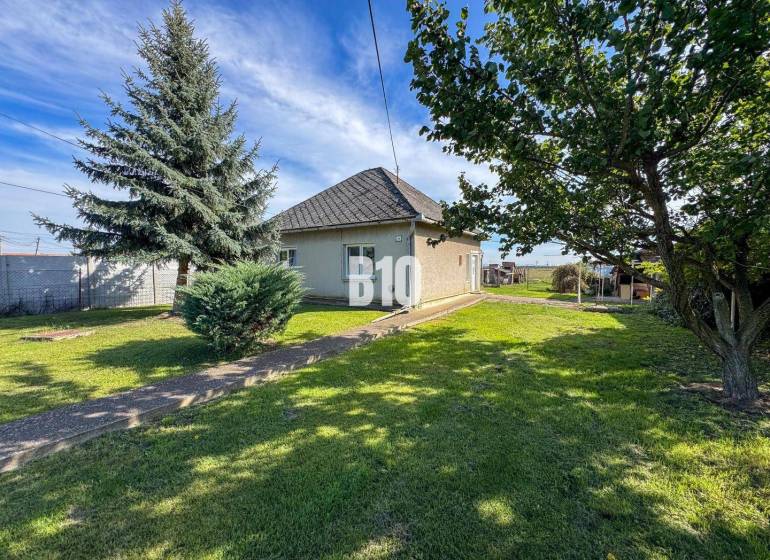 Rodinný dům v Ondrejovcích obklopený zeleným trávníkem a stromy v prostorné zahradě.