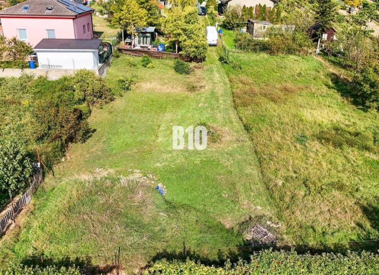 Pozemky - bydlení v Nitře s upravenou zahradou a okolními domy.