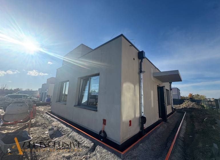 Exteriér rodinného domu v Hubicích během výstavby, slunečné počasí zesvětluje scénu.