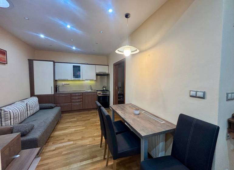 Kuchyňský kout s jídelním stolem v 1-pokojovém bytě s podlahou s dřevěným dekorem.