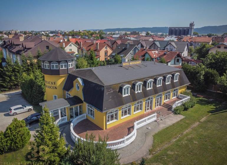 Žlutý hotel s věží, obklopený zahradou ve městě Poprad, hotely a penziony.