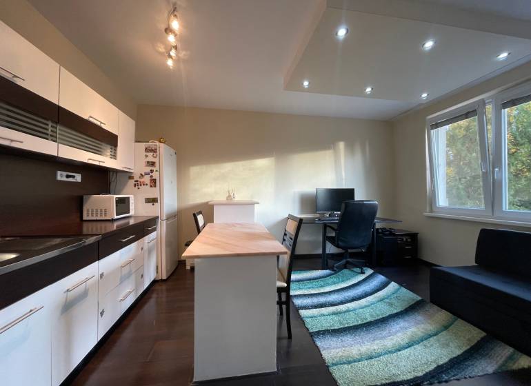 Kuchyně v 1-pokojovém bytě s podlahou s dřevěným dekorem a pracovním koutem.